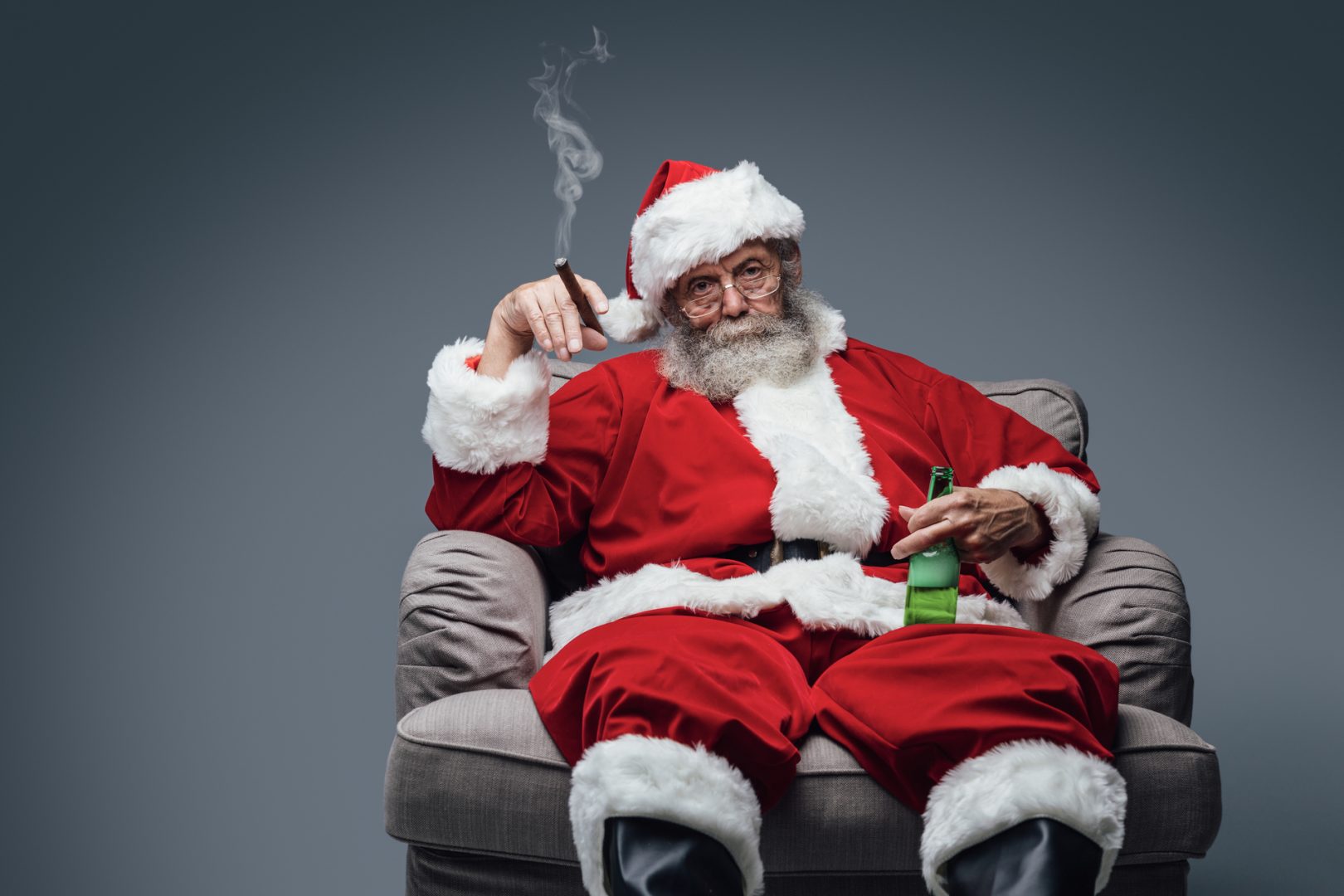 Bad Santa celebrating Christmas at home alone, he is smoking a cigar and drinking beer