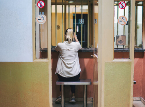 woman waits in visiting booth at jail to visit her family